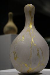 Keramická váza opravená technikou kintsugi, kde jsou praskliny vyplněny zlatem, symbolizuje transformaci bolesti a ztráty v novou krásu a sílu. Stejně jako v našem životě, i zde se zlomená místa stávají nejsilnějšími a nejviditelnějšími částmi celku.