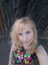 Ajasta, vztahová alchymistka a terapeutka s 26 lety praxe, v parku v květovaných šatech - autorka článku o 4 krocích empatického naslouchání, které zachrání vztah.