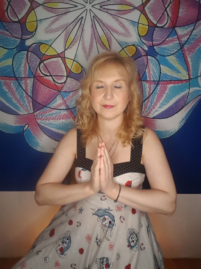 Mgr. Ajasta, vztahová alchymistka, v meditaci s rukama složenýma v gestu vděčnosti před barevnou mandalou — symbol vcítění a návratu k sobě jako prvního kroku ke změně vztahu.
